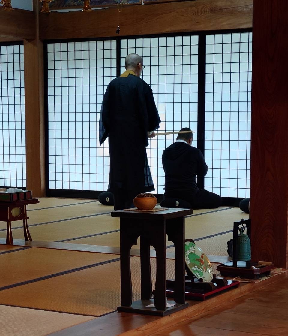 長善寺の本堂で副住職が座禅の姿勢を案内している様子